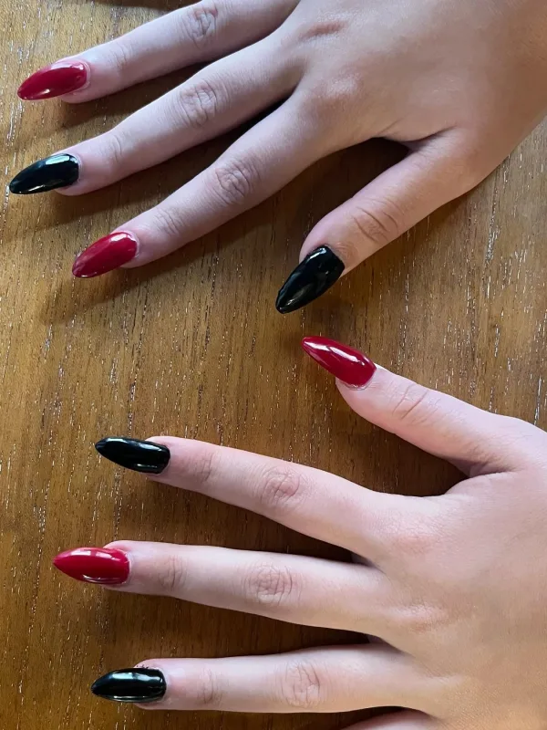 Manicura con uñas largas en forma almendrada, esmaltadas en rojo y negro brillante.