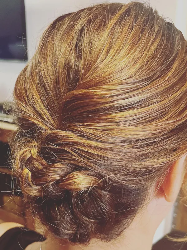 Recogido elegante con trenza en cabello castaño con reflejos dorados.